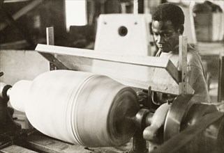 Craftsman operating a lathe, Ghana. A craftsman operates a wood-turning lathe to decorate the shell