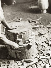 Shaping the shell of an atumpan drum. A craftsman uses a mallet on a section of timber, knocking