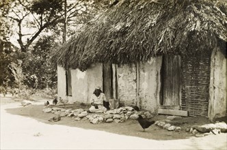 Woman and baby under the eaves. A woman and baby sit in the shade beneath the thatched eaves of a