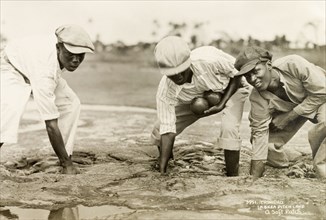 Planting bombs at the Pitch Lake. Three labourers plant bombs into a soft patch of asphalt at the