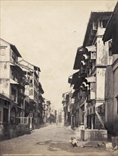 A street in Fort, Bombay. Multi-storeyed, balconied buildings flank a street in the downtown