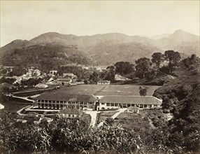 The Barracks', Kandy. A double-storey colonnaded building with a recreation ground. Identified by