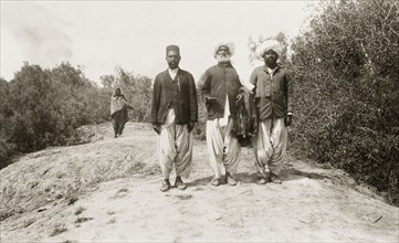 Khan Laghari with his two sons. An elderly Indian man, identified as Khan Laghari, walks along a