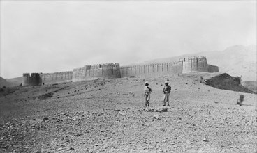 Fort wall in Kohistan . Two turbaned figures stand outside a hill fort in Kohistan, which features