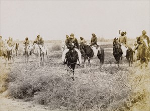 Indian men on horseback. A group of men in traditional Indian dress ride through a scrub landscape