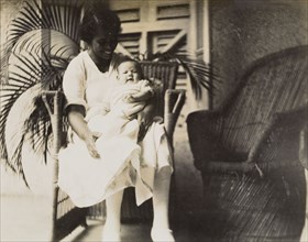 An Indian ayah with an infant. An Indian ayah (nursemaid) called Nannie sits on a veranda, cradling