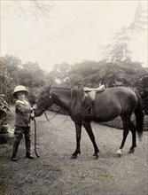 Owen with a pony, India. A European boy, Owen, wears a solatopi hat as he poses for the camera