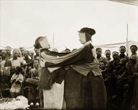 A masked performance. An amused audience looks on as two masked figures perform at an outdoor
