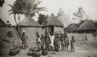 Young water carriers in Bida. A group of adolescents and children stand outside a cluster of