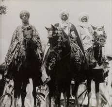 Nupe chiefs attend Sallah celebrations. Three Nupe chiefs dressed in ceremonial attire ride