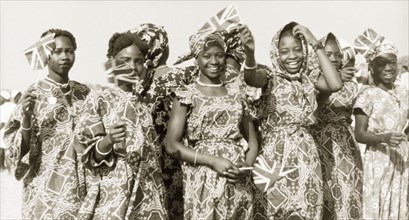 Flags for Queen Elizabeth II, Kaduna. Young women in traditional Nigerian dress wave union jack