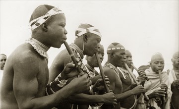 Nigerian pipe players. A group of Nigerian musicians gather to play pipes. Naked from the waist up,