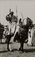 Nigerian chief on a caparisoned horse. A Nigerian chief poses with a spear in his hand as he rides