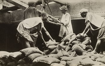 Loading sacks of tin ore at Iddo. Nigerian labourers load sacks of tin ore onto a freight car at