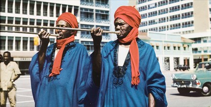 Trumpeters from North Nigeria'. Two musicians in traditional Nigerian dress play long trumpets on a