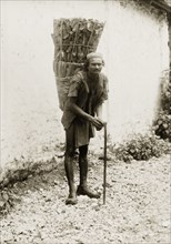 Indian man carrying firewood. An Indian man leans on his walking stick as he poses for the camera