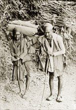 Indian couple on a rural road. An Indian couple walk along a road, carrying cumbersome bundles of