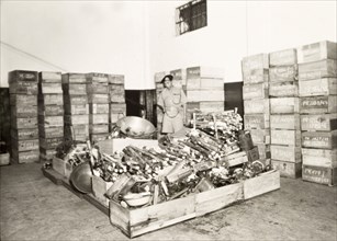 Confiscated opium equipment. An officer of the Singapore Police stands over a haul of confiscated