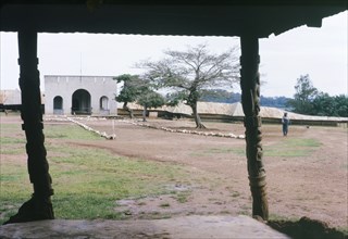 Yoruba chief's palace. View from beneath a porch with carved wooden pillars, looking towards the