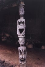 A Yoruba wood carving. A Yoruba wood carving of two women kneeling one on top of the other. In