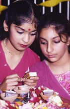 Lighting candles for Diwali. Two girls in traditional Indian dress light candles to celebrate