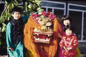 Children with a Chinese dragon. Three children pose with a traditional Chinese dragon during