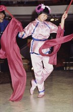 A traditional Chinese ribbon dance. A girl in traditional Chinese dress performs a dance with red