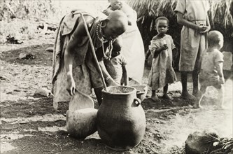 Kikuyu woman crafting pottery. A Kikuyu woman makes a clay pot outdoors at a "family pottery", a