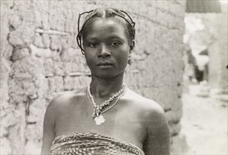 A young Asante woman. Head and shoulders portrait of a young Asante (Ashanti) woman. Her hair is