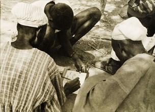 Adult literacy campaign, Gold Coast. A student teacher helps men to read from a book during a