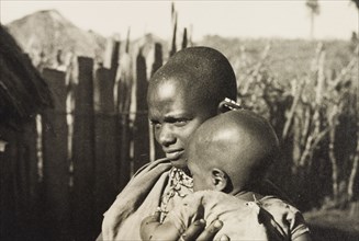 Kikuyu mother and baby. A Kikuyu baby is cradled by its mother, a woman identified in an original