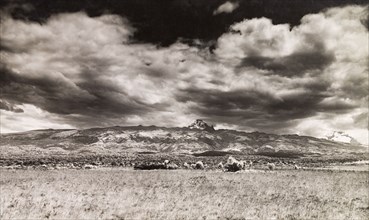 Ominous clouds over Mount Kenya. View across a grassy landscape looking towards Mount Kenya, where