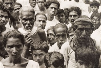 A crowd of Ceylonian people. A tightly packed crowd of people gaze solemnly into the camera. Ceylon
