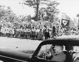 Waving goodbye to Princess Elizabeth. Crowds of schoolchildren wave union jacks flags as a car
