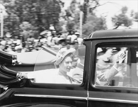 Princess Elizabeth drives past. Princess Elizabeth and the Duke of Edinburgh wave to crowds of