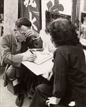 Letter-writing service on a Hong Kong street. A Chinese scribe sits at his street stall,