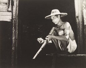 Smoking a bamboo pipe. A Chinese worker enjoys his bamboo pipe during a smoking break. Hong Kong,