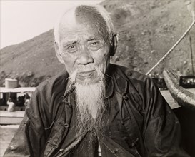 An elderly Chinese fisherman. Portrait of an elderly fisherman sitting on a boat in a Hong Kong