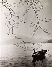 Fishing in a Hong Kong bay. A fisherman casts his net into the tranquil waters of a Hong Kong bay.