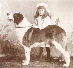 British girl posing with pet dog, India. A studio portrait of a young British girl posing with a