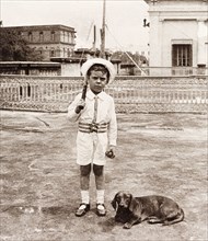Playing cricket on a rooftop garden, Calcutta. Six year old James Murray, accompanied by his pet