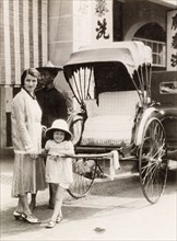 Posing with a rickshaw, Kuala Lumpur. A British woman and her daughter pose with a rickshaw during
