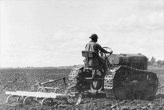 Ploughing in the Uasin Gishu plateau. An African farm hand uses a tractor to plough a field in the