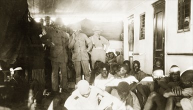 African prisoners of war on a British ship. Indian troops sit and stand behind three British Army