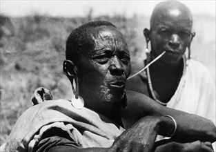 An elderly Kikuyu man. Portrait of an elderly Kikuyu man with a metal earring. Behind him sits a