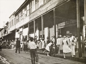 Frederick Street, Port of Spain. Crowds bustle about on Frederick Street outside a row of
