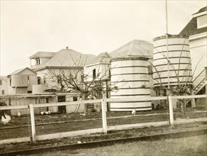 Water butts in a colonial garden, Belize. The rear garden of a colonial house, containing a chicken