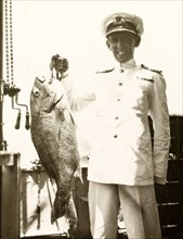 A fish caught on HMS Dauntless. The Captain of HMS Dauntless poses proudly on the ship's deck