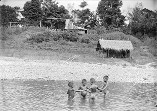 Children playing in water, Burma. Four young Burmese children stand in a circle holding hands as