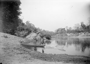 Burmese fisherman. A fisherman casts his net into the shallows of a river from the bow of his canoe